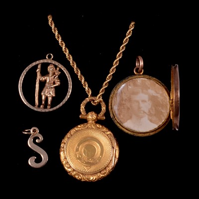 Lot 289 - A yellow metal circular locket on a chain, rose metal locket, St Christopher and letter S charm.