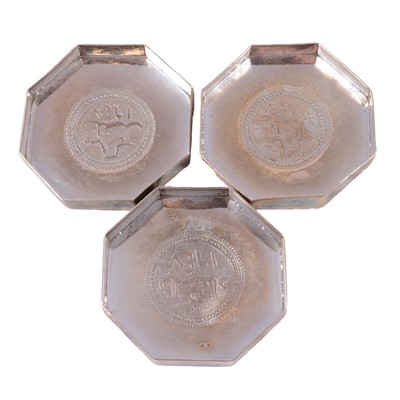 Lot 299 - Three octagonal white metal dishes with Arabic emblem and date to centre.