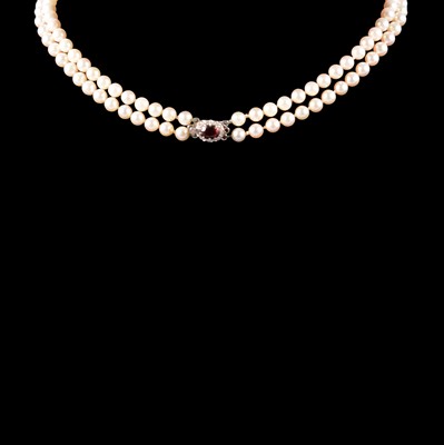 Lot 372 - A two row cultured pearl necklace with garnet and diamond clasp.