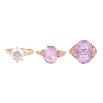 Lot 57 - Two amethyst solitaire rings, and a synthetic white stone solitaire ring.