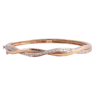 Lot 213 - A 9 carat yellow and white gold diamond set half hinged bangle.