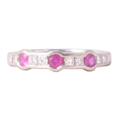 Lot 52 - A ruby and diamond half eternity ring.