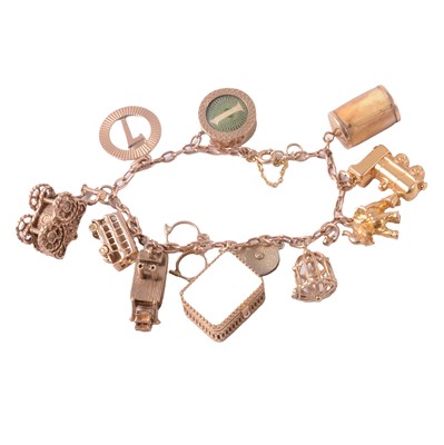 Lot 302 - A 9 carat yellow gold bracelet with twelve charms attached.