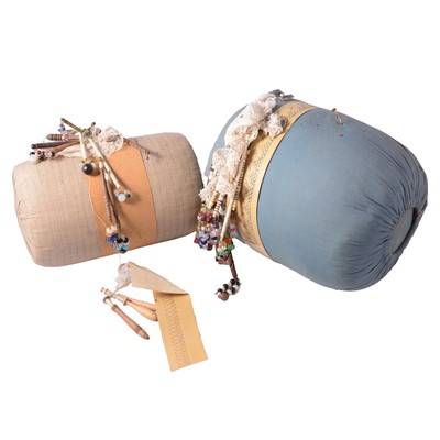 Lot 135 - A collection of wooden and bone pillow lace bobbins on cushions and patterns.