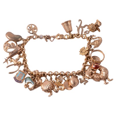 Lot 287 - A yellow metal charm bracelet with charms attached.