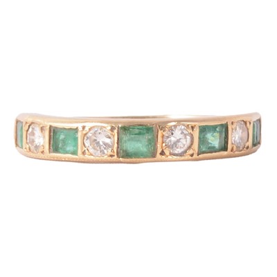 Lot 24 - An emerald and diamond eternity ring.