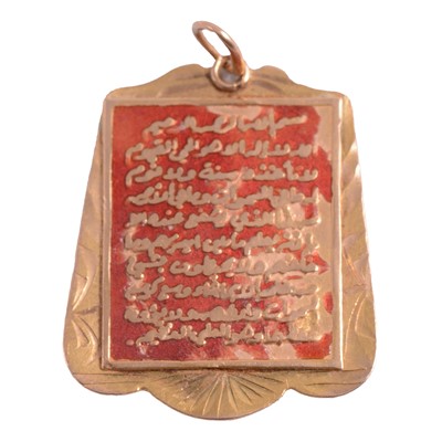 Lot 240 - A yellow metal and red enamel Koran pendant.
