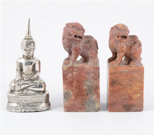 Lot 114 - Two carved red stone scroll weights and a white metal Eastern figure of Buddha (3).