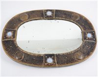 Lot 243 - A small Arts and Crafts oval mirror, mounted with opalescent cabochons