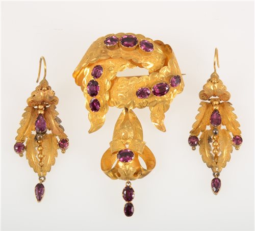 Lot 265 - A Victorian yellow metal brooch and earrings suite set with almandine garnets, ribbon design with dropper to base, total gross weight approximately 13.8gms. (3)