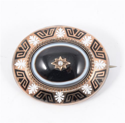 Lot 191 - A Victorian mourning brooch, an oval black agate set to centre with a decorative border of black and white enamel, vacant locket back, overall dimensions 40mm x 35mm.
