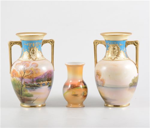 Lot 7 - A pair of Noritake twin-handled vases, painted with a bridge and small village scene, gilt border, 18cm, and a Noritake vase, painted with a pastoral scene, 11cm. (3)