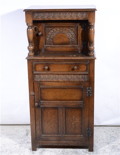 Lot 414 - Reproduction oak court cupboard, of small size, carved decoration, arcaded panelled door under a recess with a single drawer and panelled door, width 61cm, height 132cm
