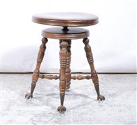 Lot 410 - Beech adjustable piano stool, circular seat, turned and ringed legs, glass ball and claw feet, minimum height 49cm.