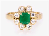 Lot 244 - An emerald and diamond oval cluster ring, the rectangular step cut emerald four claw set and surrounded by eight brilliant cut diamonds in an all yellow metal mount marked 750, ring size I.