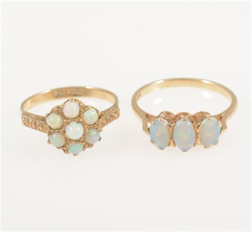 Lot 225 - A 9 carat yellow gold ring set with three oval cabochon opals, ring size M and a 9 carat yellow gold circular cluster ring set with seven round cabochon cut opals, ring size L. (2)