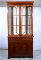 Lot 417 - Reproduction mahogany bookcase, moulded cornice, blind fretted frieze, glazed doors above cupboard, spayed bracket feet, width 102cm, depth 42cm, height 214cm.