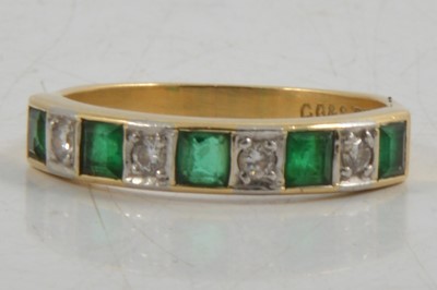 Lot 260 - An emerald and diamond half eternity ring.