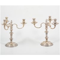 Lot 179 - A near pair of silver George II style small three-light candelabra by William Comyns & Sons Ltd, round bases, broad drip pans, London 1972 and 1974, 17cm high, 17cm at widest point