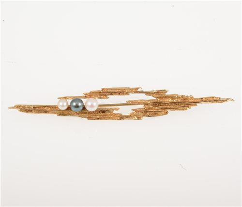 Lot 266 - A 1960s 9 carat yellow gold bark textured brooch 7cm long, set with two white and one black pearl