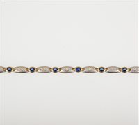 Lot 256 - A sapphire and diamond bracelet, eleven oval mixed cut sapphires spaced by ten groups of three brilliant cut diamonds in a yellow and white metal bracelet testing as 9 carat gold, 5mm wide