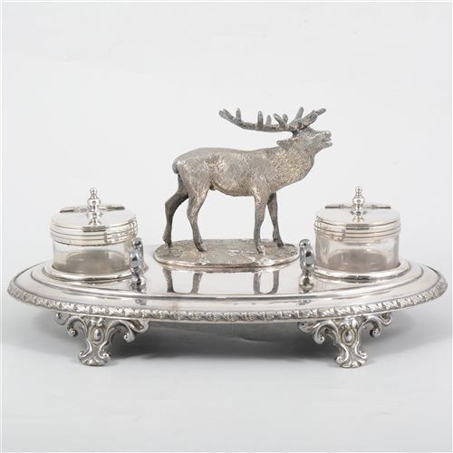 Lot 192 - A silver-plated desk stand by W F Johnson of Leicester, the oval stand with leaf border on four cast scroll feet supporting two glass inkwells with hinged plated covers