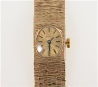 Lot 327 - Verity - a lady's 9 carat yellow gold bracelet watch, oval champagne baton dial in an integral 13mm bark textured seven brick wide bracelet 17.5cm long, hallmarked London 1976