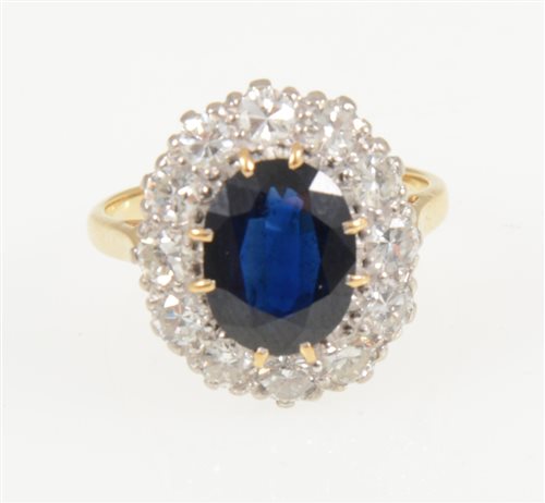 Lot 217 - A sapphire and diamond oval cluster ring, the oval mixed cut sapphire 10mm x 8mm, claw set and surrounded by twelve brilliant cut diamonds