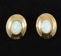 Lot 278 - A pair of opal earrings, the oval cabochon cut stones set in yellow metal mounts with polished framework, pierced fittings with retaining clips..