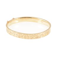 Lot 225 - A 9 carat yellow gold hollow half hinged bangle, 8mm wide flat section with a floral engraved pattern to front, approximate weight 10.8gms.