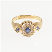 Lot 255 - A sapphire and diamond cluster ring, a circular sapphire surrounded by eight small old cut diamonds in an 18 carat all yellow gold mount with a sapphire set into each shoulder