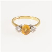 Lot 256 - A yellow sapphire and diamond three stone ring, the oval mixed cut sapphire 6.5mm x 5mm, claw set with a brilliant cut diamond to each side