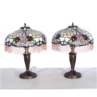 Lot 173 - A pair of modern Tiffany style table lamps, bronze effect floral bases supporting glass shades featuring red and burgundy roses, peach coloured beaded fringe around base, overall height 55cm. (2)