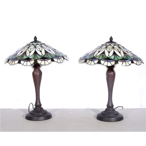 Lot 174 - A pair of modern Tiffany style table lamps, bronze effect circular fluted bases supporting coolie glass shades in the art deco style with green. blue and cream panels, overall height 50m. (2)