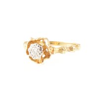 Lot 204 - A diamond solitaire ring, the brilliant cut stone illusion set in a yellow and white metal single stone mount, molten finish floral surround to diamond, bamboo design shoulders