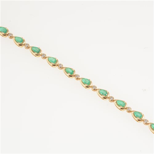 Lot 281 - An emerald and diamond line bracelet, eighteen pear shaped emeralds individually claw set and spaced by seventeen small diamonds in 18 carat yellow gold, overall width 4.8mm, length 19cm