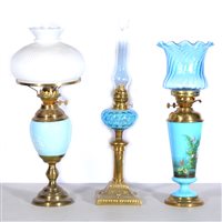 Lot 166 - Three oil lamps, to include Duplex, white opaque upside-down bowl-shaped shade, blue ceramic reservoir with white floral decoration, brass circular column and base, 62.5cm... (3)