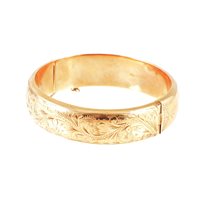 Lot 277 - A 9 carat yellow gold 15mm wide hollow half hinged bangle, scroll decoration to front, approximate weight 23.9gms.