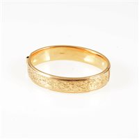 Lot 278 - A 9 carat yellow gold 12mm wide hollow half hinged bangle, scroll decoration to front, approximate weight 17.3gms.