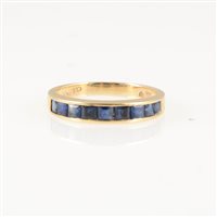 Lot 248 - A sapphire half eternity ring, nine square cut stones channel set in an all yellow metal mount, 3.4mm wide at front, shank marked 585