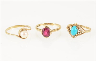 Lot 181 - Three 9 carat yellow gold dress rings, one set with an oval synthetic ruby, one with an oval cabochon cut turquoise and another with a 5.6mm cultured pearl, ring sizes M/O.