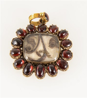 Lot 186 - A garnet memorial pendant, fourteen oval cabochon cut garnets in closed back settings and surrounding a rectangular glass locket centre with curls of hair