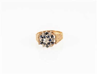 Lot 176 - A sapphire and diamond circular cluster ring, twelve sapphires claw set, seven diamond points illusion set in a 9 carat yellow and white gold mount with wide bark textured shoulders