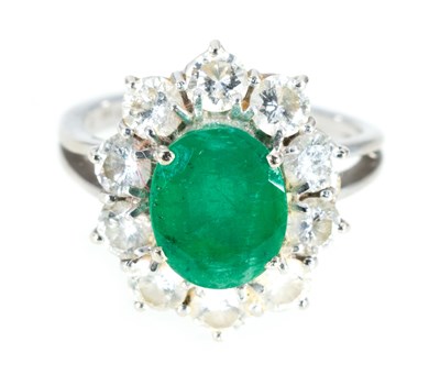 Lot 205 - An emerald and diamond oval cluster ring.