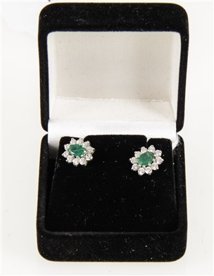 Lot 182 - A pair of emerald and synthetic white stone cluster earrings, the oval emerald surrounded by ten synthetic white stones, pierced fittings with post and butterfly.