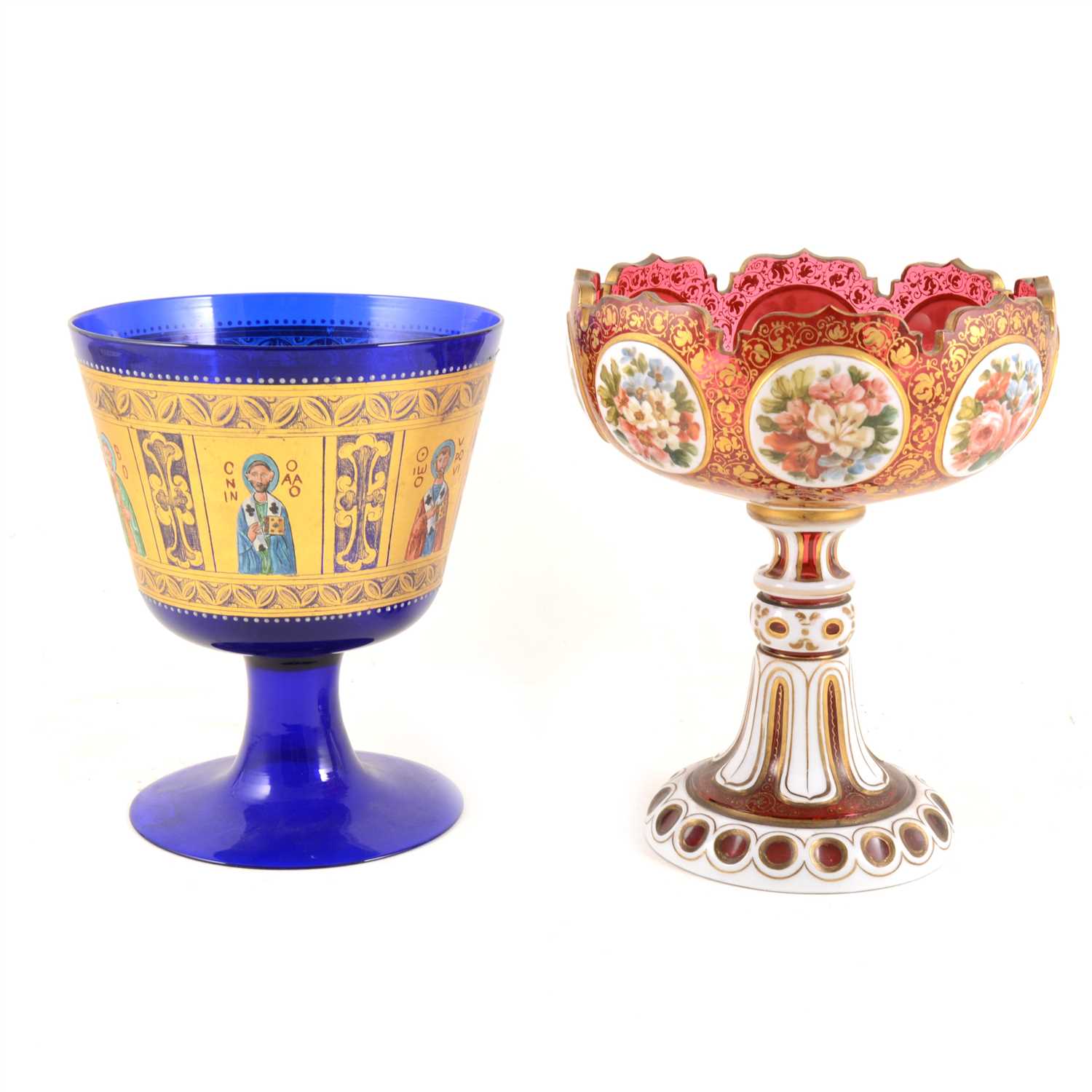 Lot 23 - A Bohemian ruby glass pedestal dish overlaid in white and gilt with eight floral vignettes, and a Bristol blue goblet with heavily gilded ecclesiastical panels depicting saints