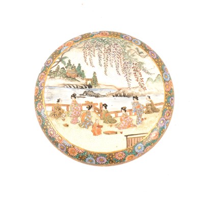 Lot 54 - A Japanese satsuma circular covered dish, cover depicting women by waterside with wisteria above them, additional decorative scenes inside lid and dish, 12.5cm diameter.