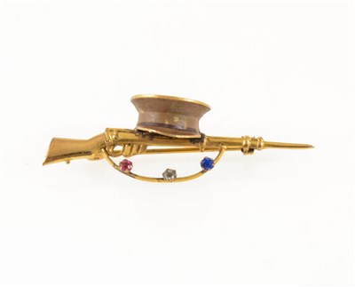 Lot 269 - A gold-plated bar brooch of military interest, a 50mm long rifle with cap and set with three paste stones, red, white and blue, Rd 641091.