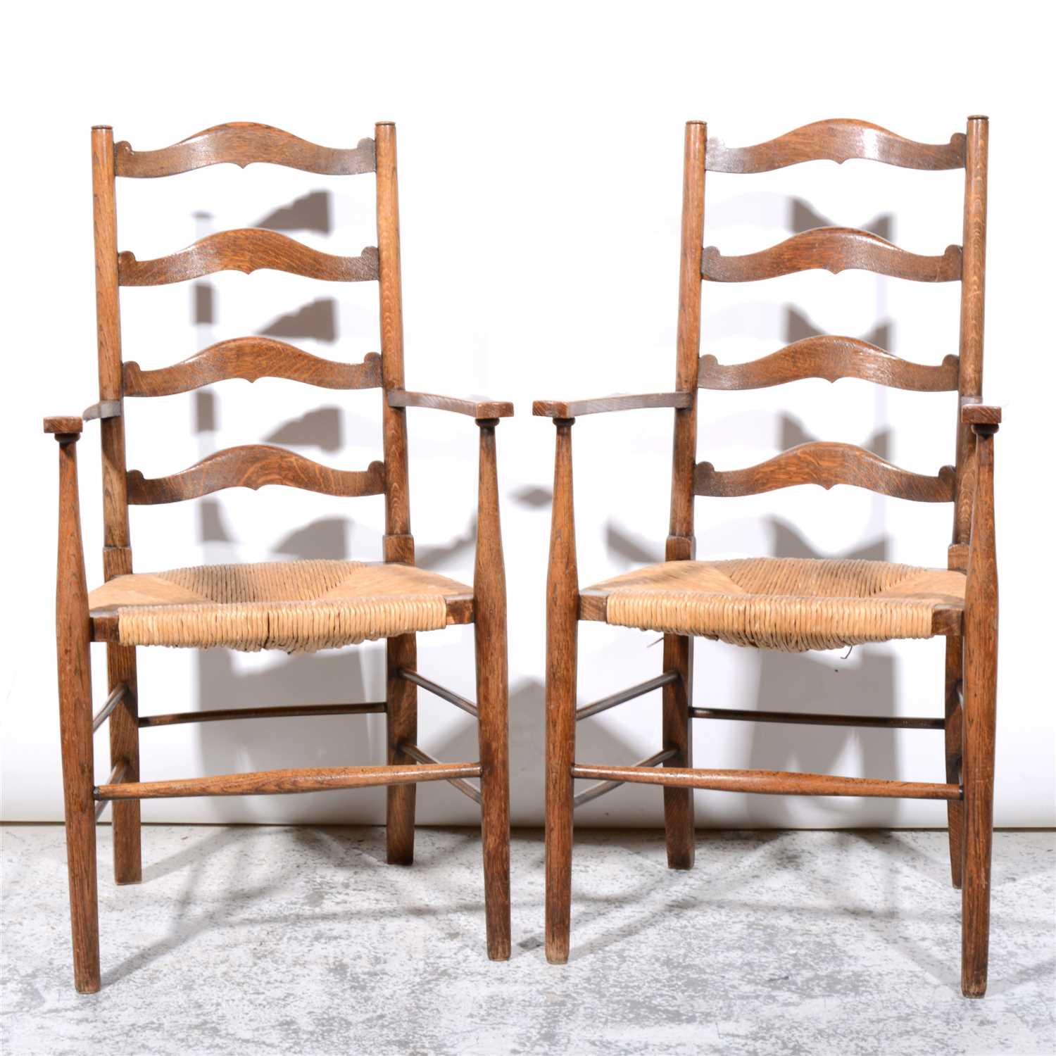 Lot 356 - Two Arts and Crafts oak framed ladder back armchairs, in the manner of Ernest Gimson