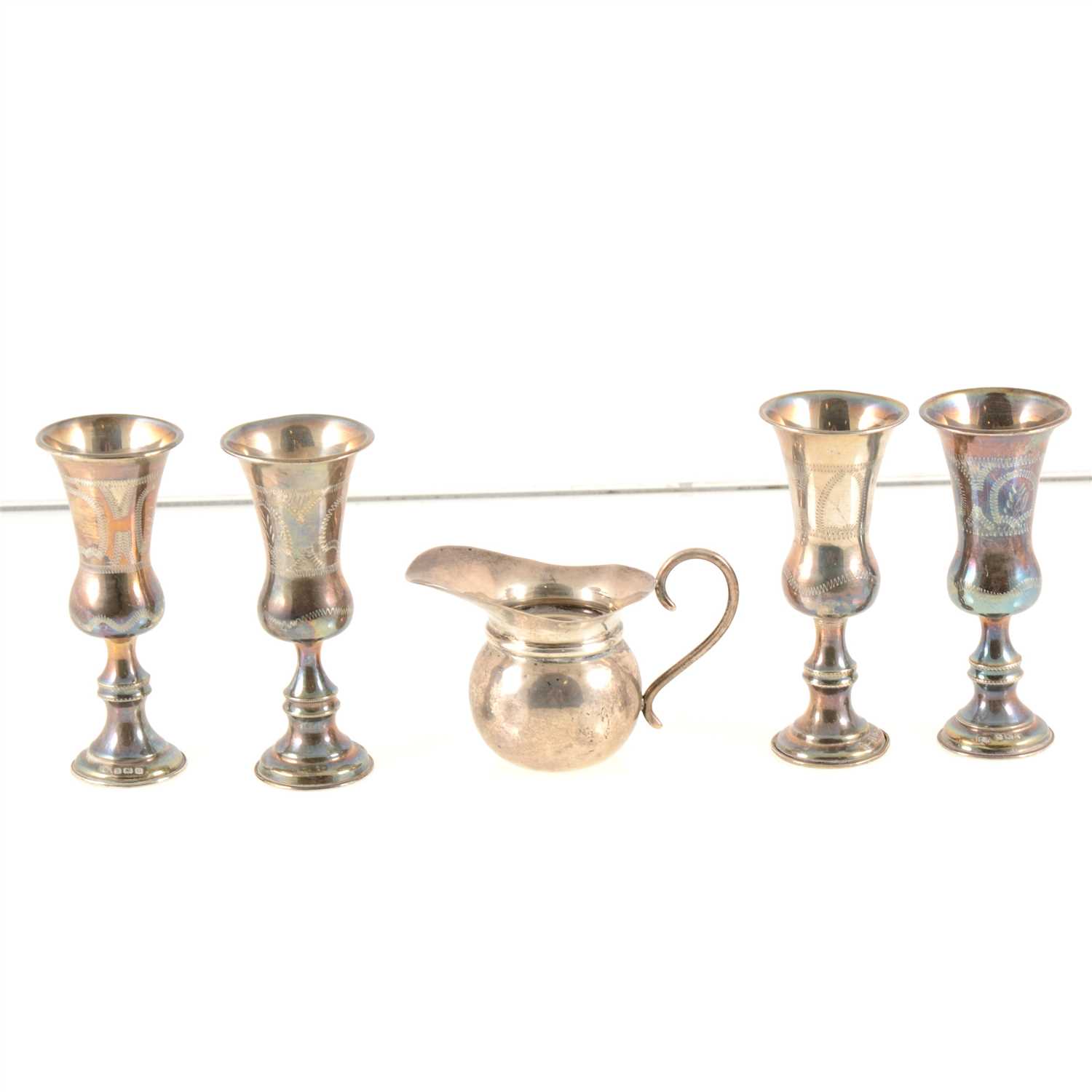 Lot 189 - Set of eight silver Kiddush cups, maker's mark J.R., Birmingham, circa 1920, 10cm, another very similar, each with slender bowls and engraved decoration, and a small Edwardian silver jug